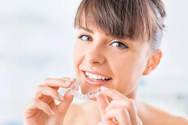Patient holding Invisalign clear aligners at a Toronto dental office